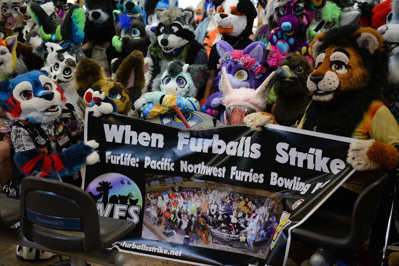 Furries assemble and hold banner for group photo.